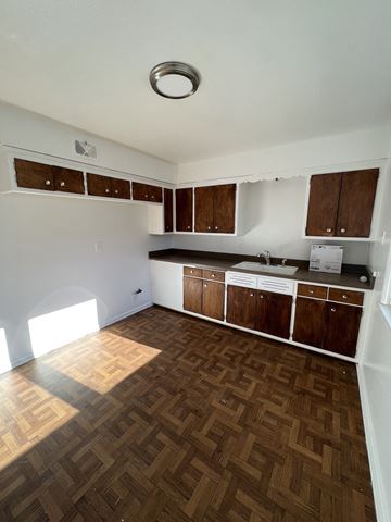 Milwaukee apartment for rent - an empty kitchen with wooden floors and wooden cabinets