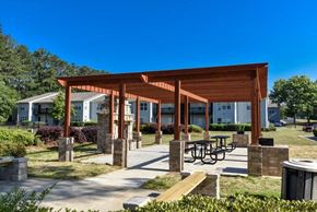 Ellenwood apartment for rent - A wooden pavilion with a picnic table in front of apartment buildings.