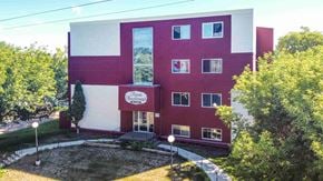 Wainwright apartment for rent - a large red and white building with trees in front of it