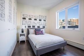 Calgary apartment for rent - A bedroom with a bed, nightstand, and a wall of pictures.