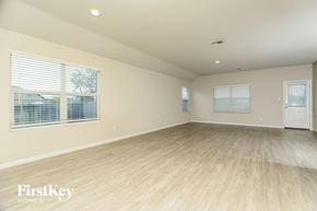 San Antonio house for rent - A spacious room with wooden flooring and two windows with blinds.