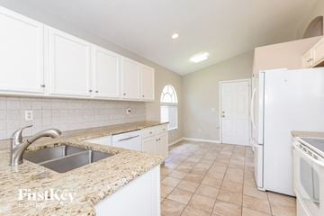 Haines City house for rent - A kitchen with white cabinets and a granite countertop.