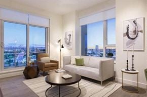 Burnaby apartment for rent - A living room with a white couch, a coffee table, and a large window with a view of the city.