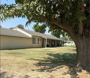 Merced house for rent - A tree is in the foreground of a house with a car in the driveway.