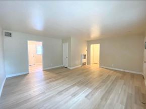 Merced house for rent - A spacious room with wooden flooring and white walls.