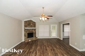 Cordova house for rent - A room with a stone fireplace and a ceiling fan.