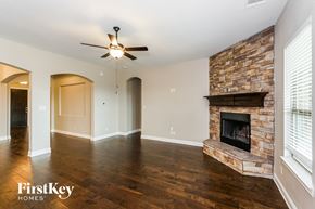 Midlothian house for rent - an empty living room with a brick fireplace and a ceiling fan