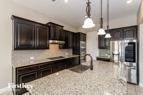 Midlothian house for rent - a kitchen with black cabinets and a marble counter top