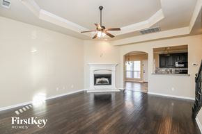 Fort Worth house for rent - A spacious living room with a fireplace and a ceiling fan.