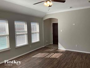 Aubrey house for rent - an empty living room with a ceiling fan and three windows