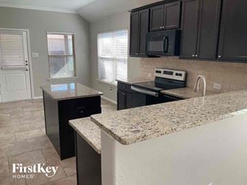 Aubrey house for rent - an updated kitchen with granite counter tops and black cabinets