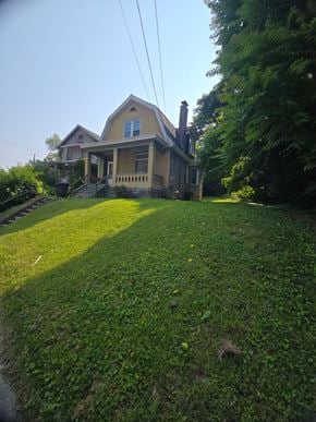 Cincinnati house for rent - A house with a yellow front and a green lawn.
