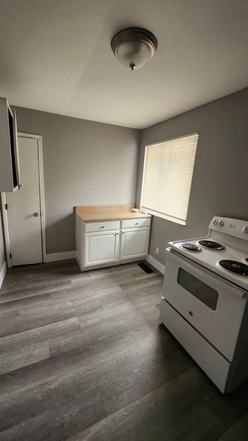 Cincinnati apartment for rent - A kitchen with a white stove top oven and a white fridge.
