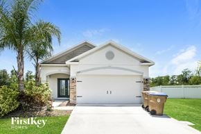 Kissimmee house for rent - a white house with a garage door and a trash can on the driveway