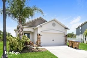 Kissimmee house for rent - a white house with a garage door and a palm tree