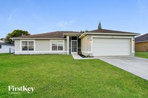 Cape Coral house for rent - a white house with a lawn and a garage door