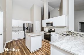 Valrico house for rent - a kitchen with white cabinets and stainless steel appliances and marble counter tops