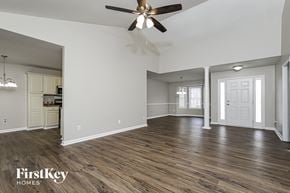 Greensboro house for rent - the living room and kitchen of an empty house with a ceiling fan