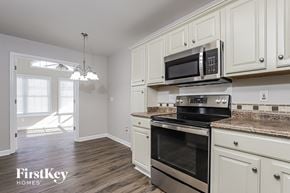 Greensboro house for rent - a kitchen with white cabinets and a stove and a microwave