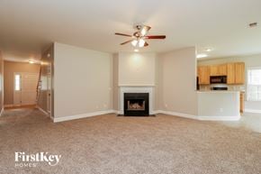 Moncks Corner house for rent - A spacious living room with a fireplace and a ceiling fan.