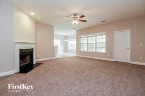 Moncks Corner house for rent - A spacious living room with a fireplace and a ceiling fan.