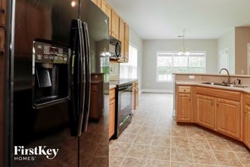 Moncks Corner house for rent - A kitchen with a black refrigerator and wooden cabinets.
