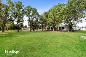 Lehigh Acres house for rent - a large yard with trees and a house in the background