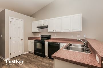 Lehigh Acres house for rent - a kitchen with pink granite counter tops and black appliances
