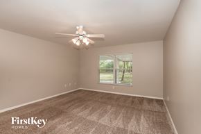 Lehigh Acres house for rent - a bedroom with carpet and a ceiling fan and a window
