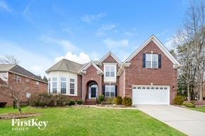 Jamestown house for rent - A brick house with a garage and a tree in front.