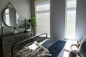 Ames apartment for rent - A bedroom with a bed, a dresser with a mirror, and a plant on the dresser.