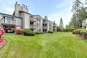 Tacoma apartment for rent - the view of an apartment building with a green lawn and flowers