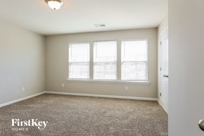 Mooresville house for rent - a bedroom with three windows and a carpeted floor