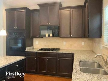 Conyers house for rent - A kitchen with dark brown cabinets and a granite countertop.
