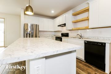 Surprise house for rent - a kitchen with white marble counter tops and black appliances and white cabinets