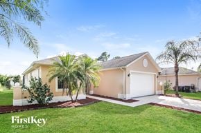 North Port house for rent - a beige house with palm trees in front of it