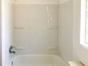 Show Low house for rent - A white bathroom with a tub and a window.