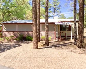 Show Low house for rent - A house with a brown roof and white walls is surrounded by trees.
