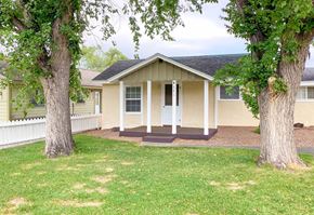 Show Low house for rent - A small house with a porch is surrounded by trees.
