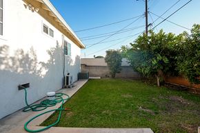 Monterey Park apartment for rent - the backyard of a house with a garden and a hose watering the grass