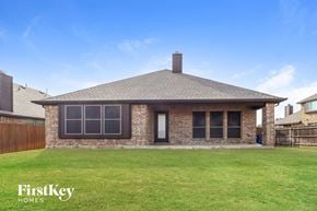 Burleson house for rent - A house with a brown roof and a chimney is surrounded by a grassy lawn.
