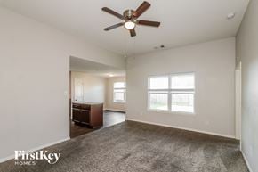 Brookshire house for rent - A spacious room with a ceiling fan and a carpeted floor.