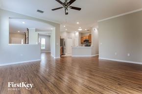 Parrish house for rent - an empty living room with a ceiling fan and a kitchen