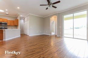 Parrish house for rent - an empty living room and kitchen with wood floors and a ceiling fan
