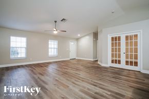 Cape Coral house for rent - A spacious room with wooden flooring and a ceiling fan.