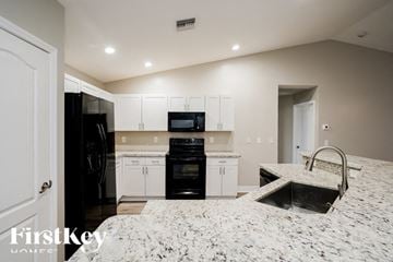Cape Coral house for rent - A kitchen with white cabinets and black appliances.