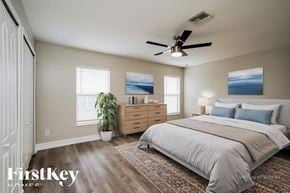 Cape Coral house for rent - A bedroom with a large bed, a ceiling fan, and a potted plant.