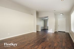 Surprise house for rent - A spacious room with wooden floors and white walls, with a door on the right side.