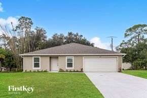 Port Charlotte house for rent - a beige house with a garage door and a lawn
