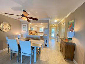 Bradenton house for rent - a dining room table with blue chairs and a ceiling fan